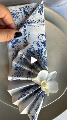 a person is holding a napkin with a flower on it in front of a plate