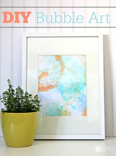 a potted plant sitting on top of a table next to a framed art piece