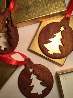 three wooden ornaments with red ribbon on top of each ornament, and one is shaped like a christmas tree