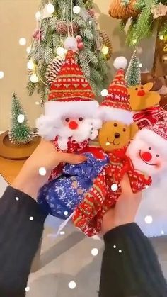 two people holding teddy bears in front of a christmas tree