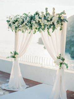 an outdoor ceremony with white flowers and greenery