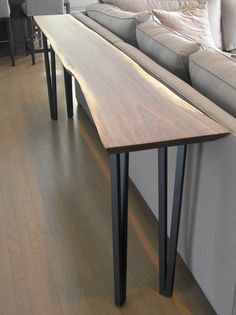 a long wooden table sitting on top of a hard wood floor next to a couch