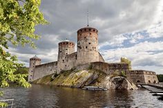 an old castle sits on top of a hill next to the water and is surrounded by trees