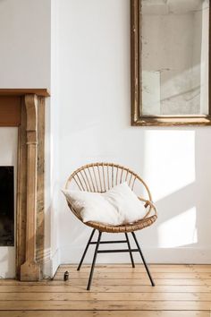 a wicker chair sitting in front of a fire place with a pillow on it