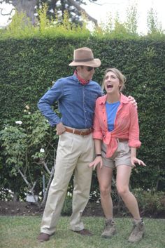 a man and woman standing next to each other in front of a hedge with their mouths open