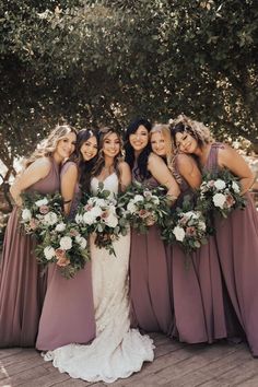 a group of women standing next to each other wearing dresses and holding bouquets in their hands