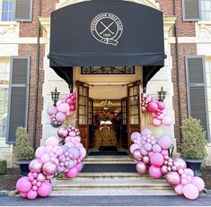 an entrance to a building decorated with pink and purple balloons