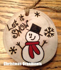 a wooden ornament with a snowman painted on it's face and the words let it snow