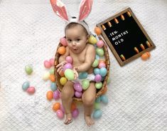 a baby is sitting in a basket with easter eggs around it and an inscription that reads ten months old