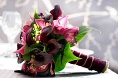 a bouquet of flowers sitting on top of a table next to a wine glass and knife