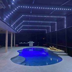 an indoor swimming pool with blue lights on the ceiling and white lighting around it,