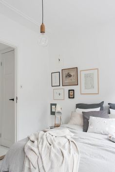 a bedroom with white walls and pictures on the wall