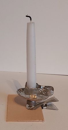 a white candle sitting on top of a table next to utensils