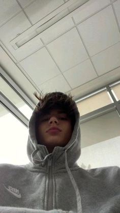 a young boy wearing a nike hoodie in an office space with his eyes closed