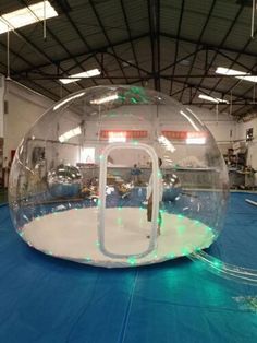 an inflatable bubble ball is on the floor inside a large warehouse with blue tarps