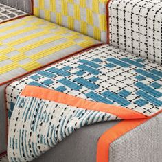 an upholstered couch with colorful pillows on it's back and seat cushions