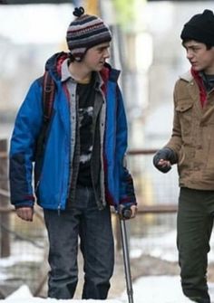 two young men are walking in the snow