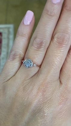 a woman's hand with a pink manicured nail polish and a diamond ring