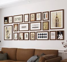 a living room filled with lots of framed pictures on the wall next to a brown couch