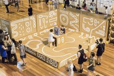 a group of people standing around a display in a room filled with wooden flooring