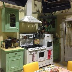 a kitchen with green cabinets and white stove top ovens in the middle of it