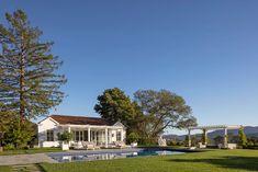 a house with a pool in the middle of it and some trees around it on a sunny day