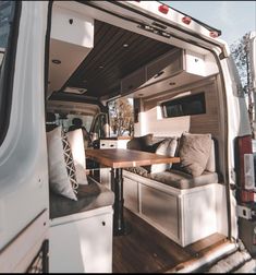 the interior of a camper van with couches and tables in the back area