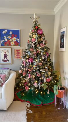 a decorated christmas tree in the corner of a living room with pictures on the wall