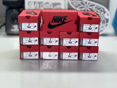 six red nike boxes stacked on top of each other in front of a black and white camera