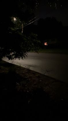 a dark street at night with a stop sign on the side of the road in front of it