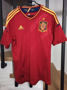 a soccer jersey hanging on a rack in a room with wooden floors and railings