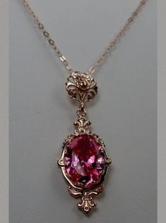 This is a rose gold plated over sterling silver Victorian reproduction pendant with a flawless simulated gemstone. The stunning man made 6 carat gem is 14mm long and 10mm wide. The pendant is 1.75" long. The necklace (if chosen) is adjustable between 18"-20". The pendant and chain are marked 925 for sterling silver. Elegant Pink 14k Rose Gold Jewelry, Formal 14k Rose Gold Pink Gold Necklaces, Formal 14k Rose Gold Pink Necklace, Pink Oval Pendant Jewelry For Wedding, Formal Pink Pendant Jewelry, Exquisite 14k Rose Gold Jewelry, Rose Gold Jeweled Necklaces For Gifts, Classic Rose Gold Cubic Zirconia Jewelry, 14k Rose Gold Jewelry With Gemstones