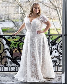 a woman in a white dress standing on a balcony with her hands on her hips