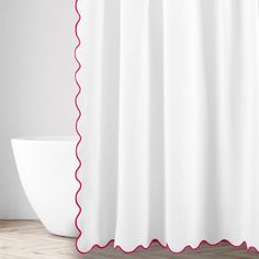 a white shower curtain with red scalloped trim on the edge and a bowl below it