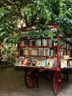 a red cart with books on it under a tree