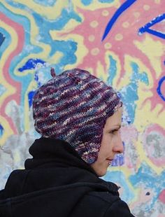 a woman wearing a knitted hat in front of graffiti