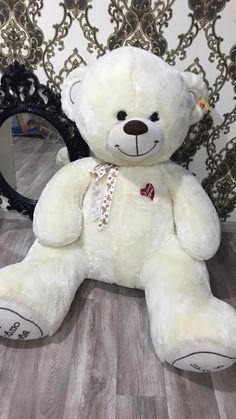 a white teddy bear sitting in front of a mirror on the floor next to a wall