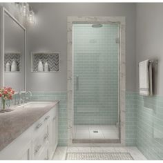 a bathroom with green tile and gold trim on the shower door, sink, and mirror