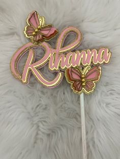 a pink and gold name cake topper on a white furnishing with butterflies