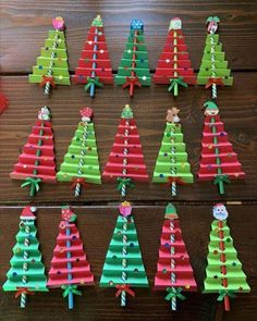 christmas trees made out of construction paper are displayed on a wooden table with other decorations