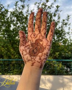 a person's hand with hennap on it and trees in the background