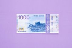 a bank note with the image of a wave on it is laying against a purple background