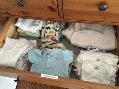 an open drawer filled with lots of baby clothes