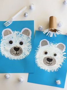 two polar bear crafts on blue paper with white pom poms