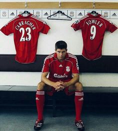 a man sitting on a bench in front of a soccer jersey hanging on the wall