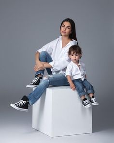 a woman and child sitting on top of a white box