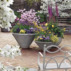 two flower pots sitting next to each other on a brick patio