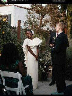 a woman in a white dress standing next to a man wearing a suit and tie