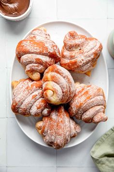 powdered donuts on a white plate with dipping sauce