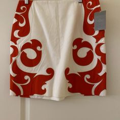 a red and white skirt hanging on a clothes hanger in front of a wall